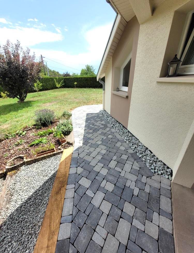 Allée en pierre contournant une habitation.