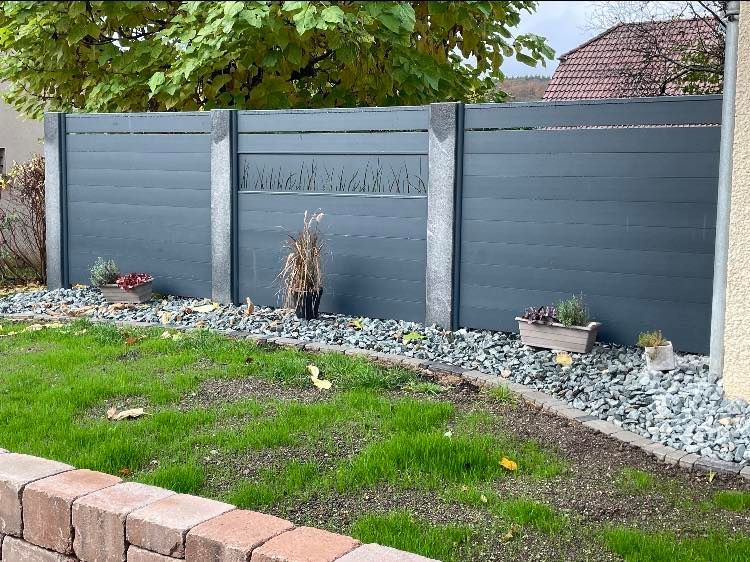 Clôture de jardin avec trois piliers en pierre.