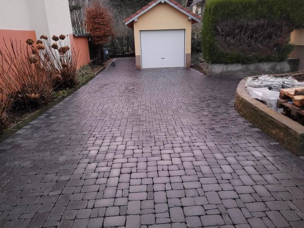 Une allée pavée menant vers une porte de garage blanche.