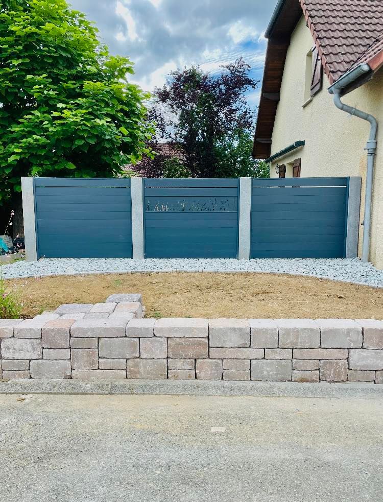 Petite clôture derrière un muret en pierre.