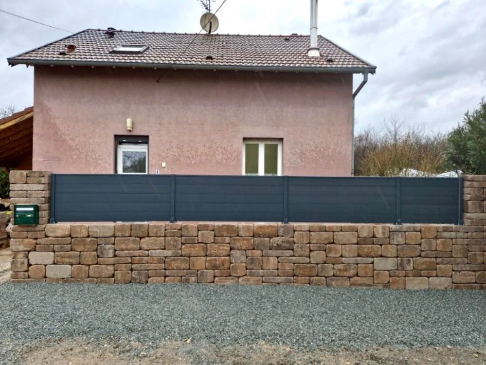 Petite clôture noir anthracite posée sur un muret en pierre.