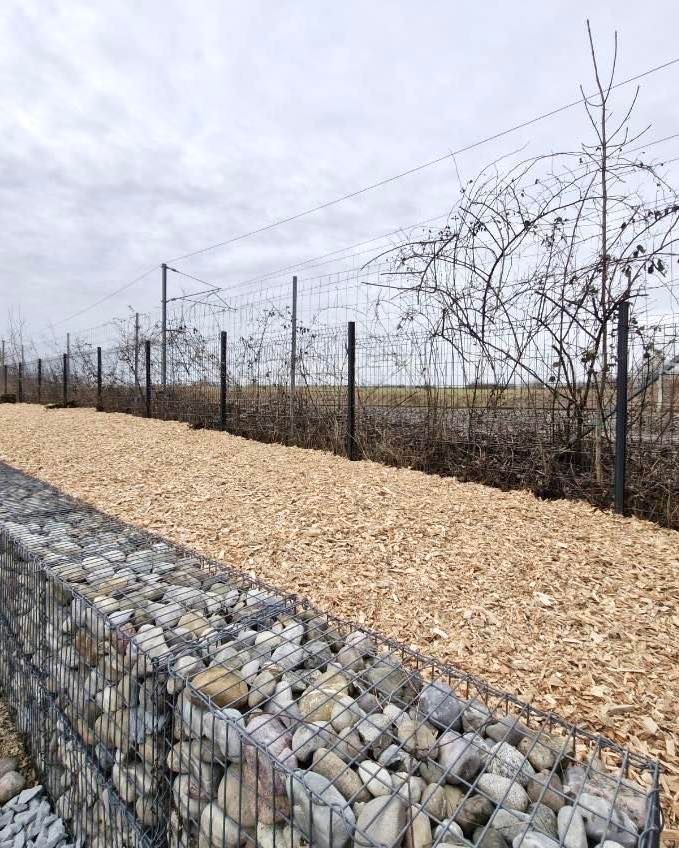 Une clôture de galets dans de la ferraille.