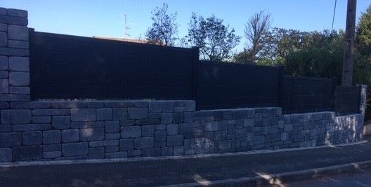 Clôture posée sur un muret en pierres