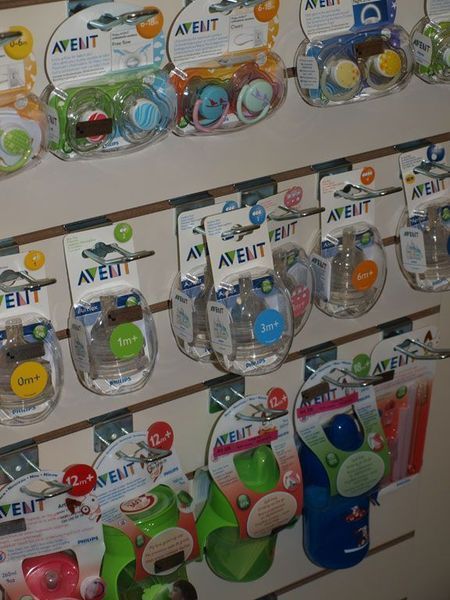 Schnuller in verschiedenen Farben, verpackt in durchsichtigem Plastik, in einem Verkaufsregal ausgestellt.