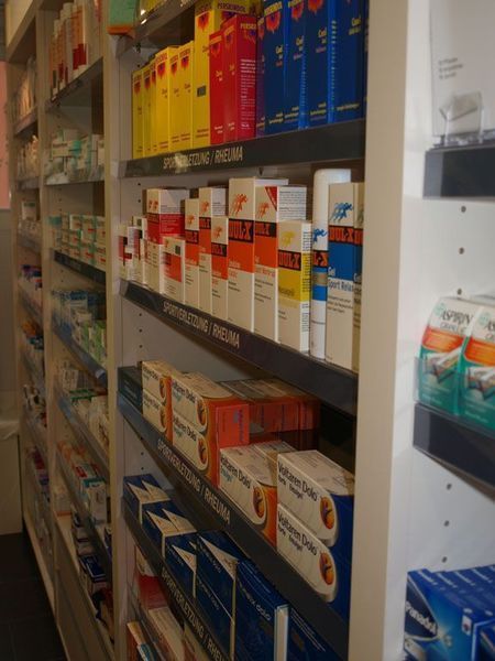Regale in einer Apotheke, gefüllt mit verschiedenen pharmazeutischen Produkten, in bunten Schachteln und mit Etiketten.