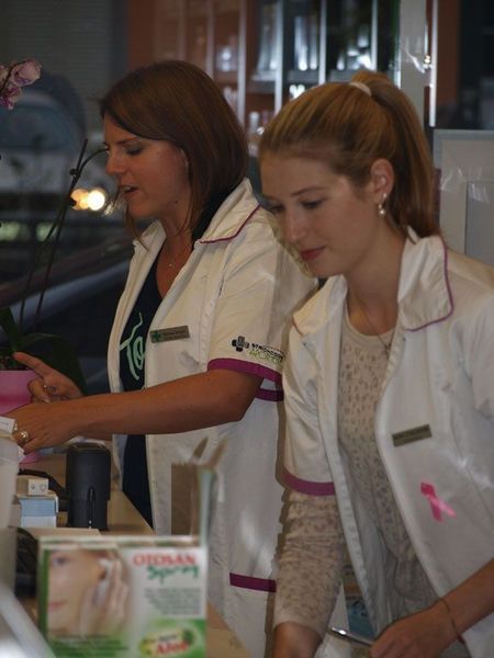 Zwei Apothekenangestellte in weissen Kitteln arbeiten hinter einem Tresen.