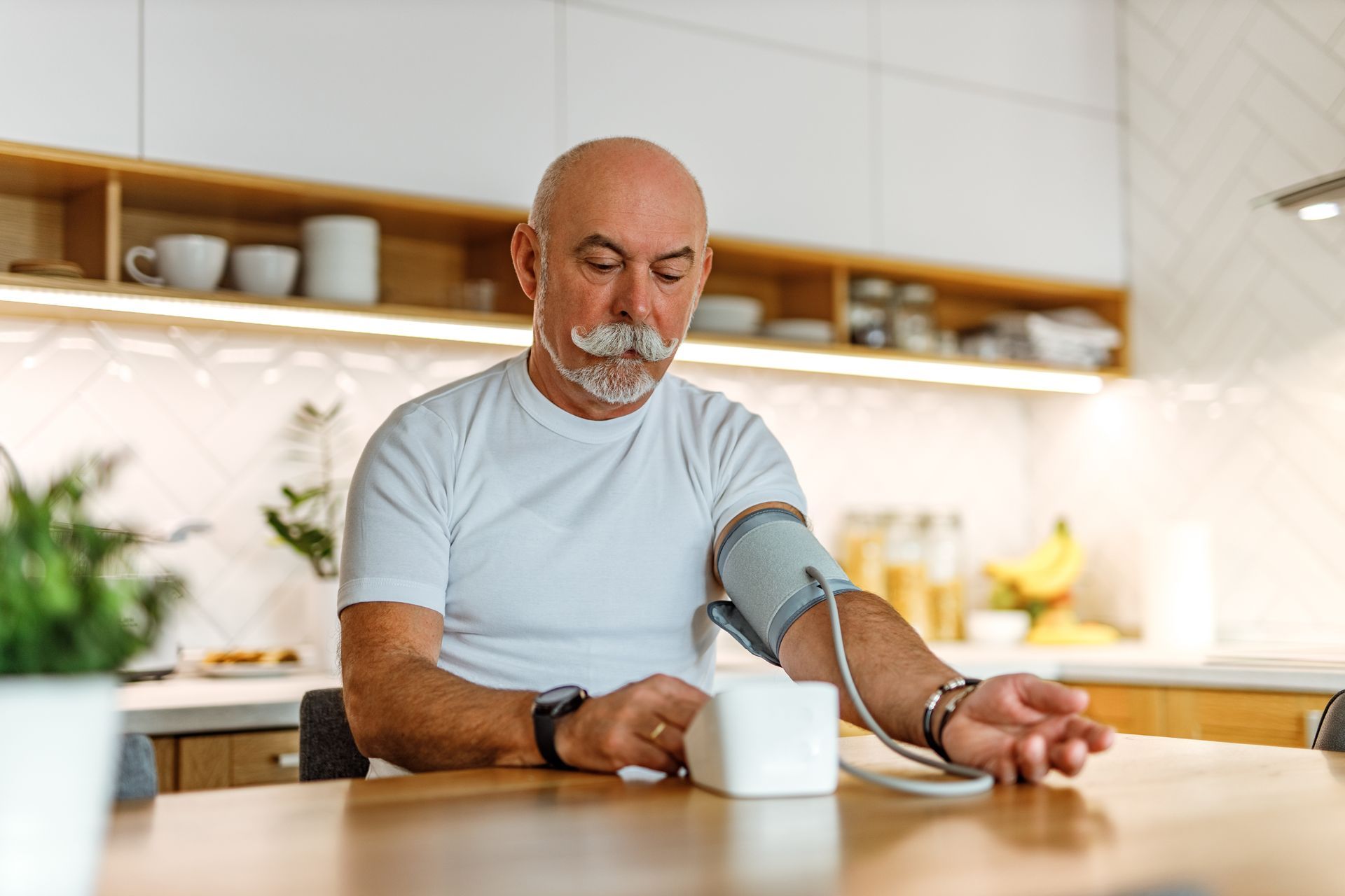 Un homme utilise un tensiomètre chez lui