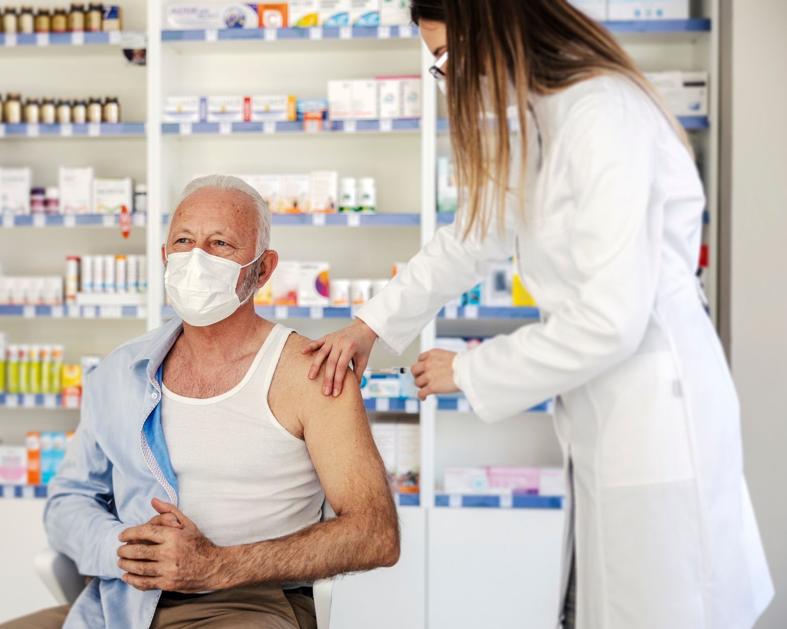 Un pharmacien administre un vaccin à un homme âgé dans une pharmacie