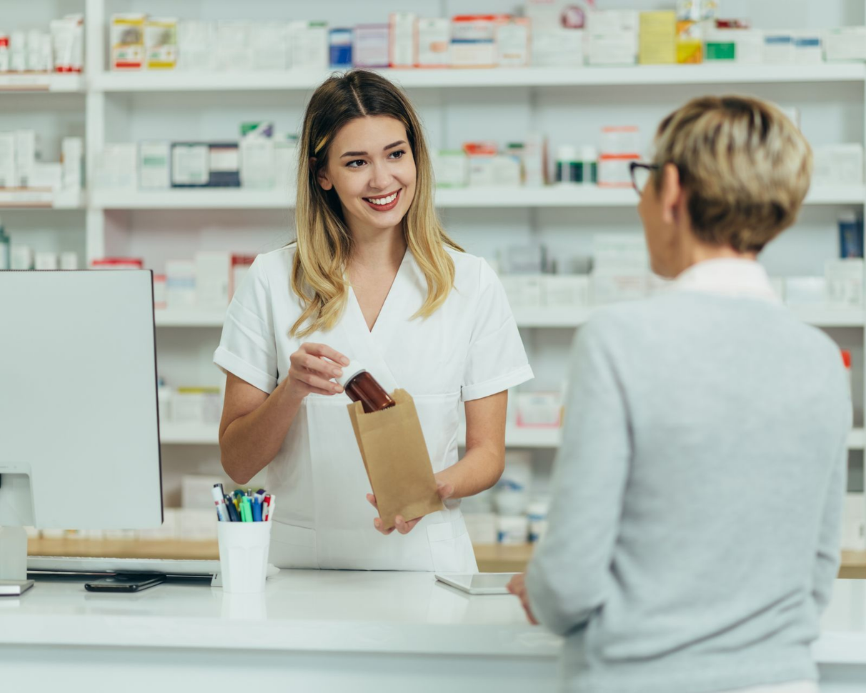 Pharmacienne place un produit de parapharmacie dans un sachet pour sa cliente