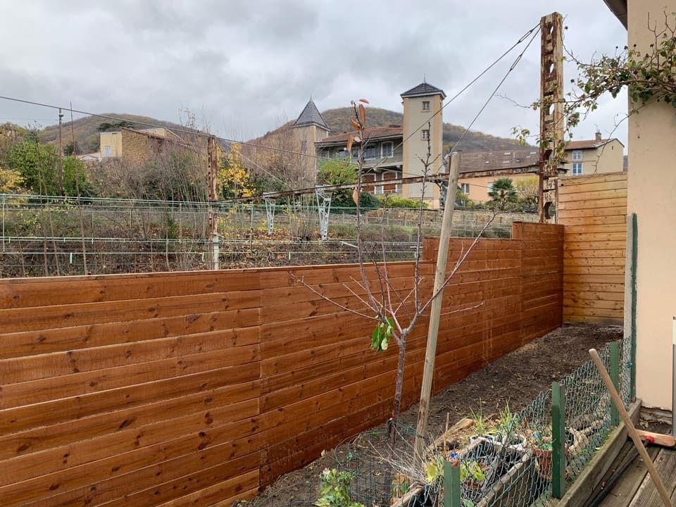 Vue sur des bâtiments et maisons derrière une grande palissade en bois