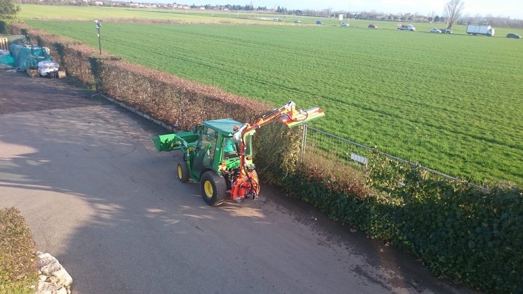 Tracteur en train de tailler une haie le long d'une route