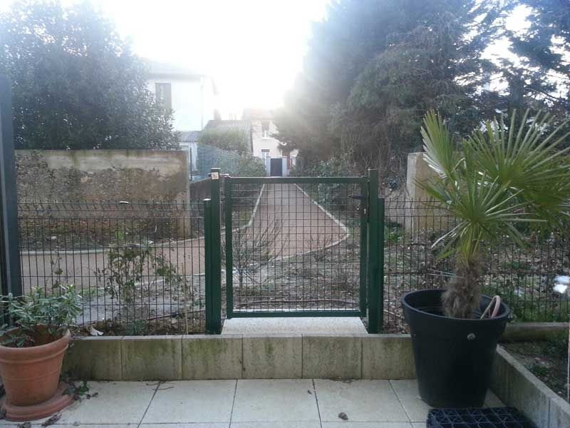 Cour intérieur via une porte d'accès fermé d'une clôture en grille