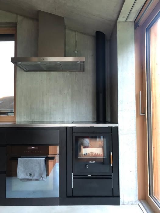 Cuisine avec armoires foncées, un poêle à bois noir avec flammes visibles