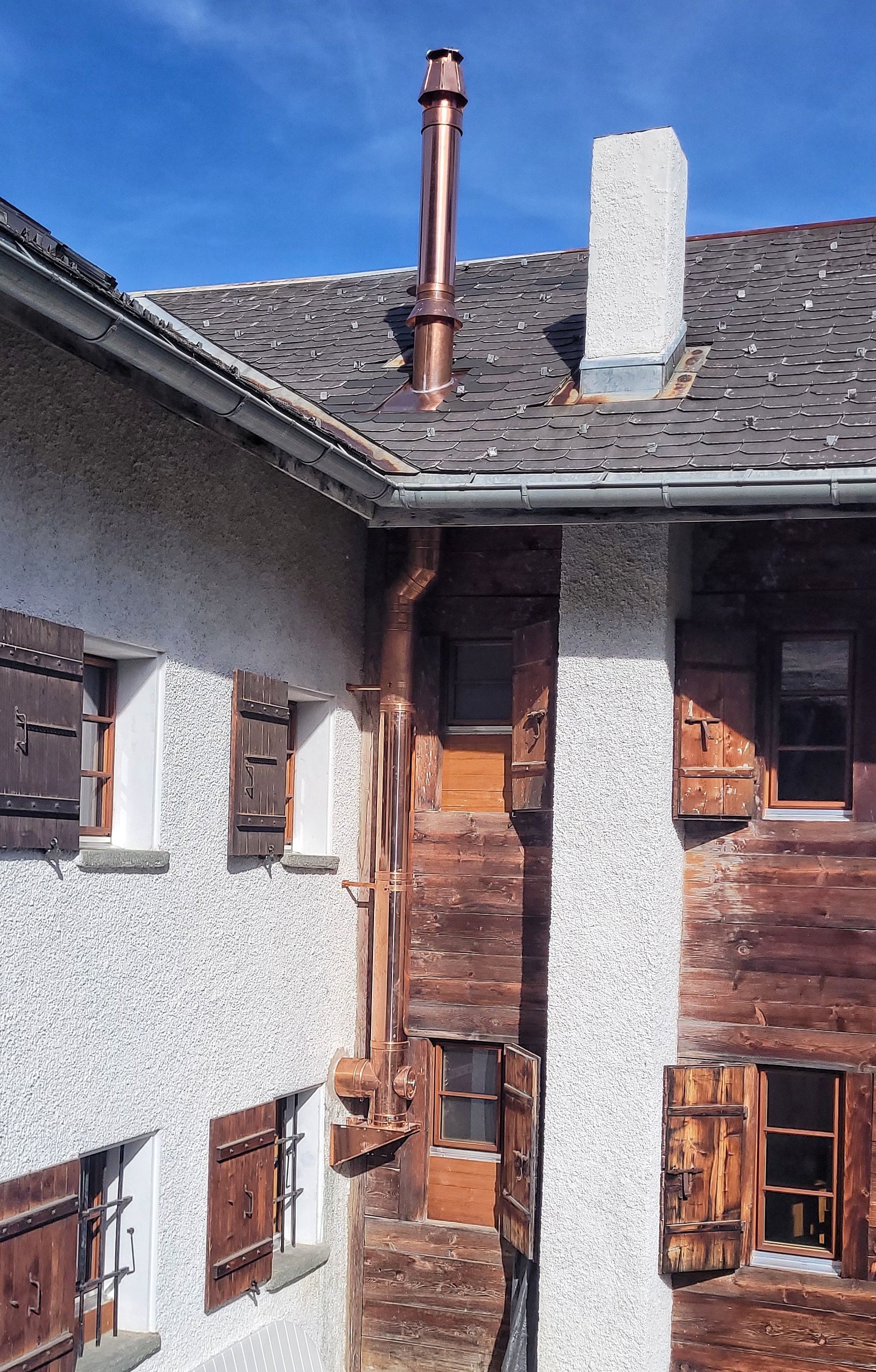 Extérieur d'un bâtiment rustique avec cheminée et gouttière en cuivre