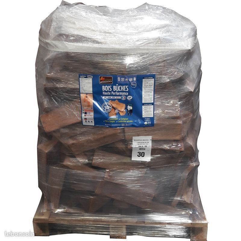 Une palette de bois de chauffage emballée dans du plastique, portant une étiquette bleue et blanche.