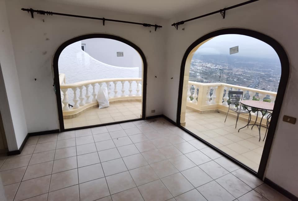Una habitación vacía con ventanas arqueadas que dan a un balcón.