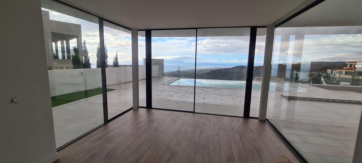 Una habitación con muchas ventanas y una piscina al fondo.