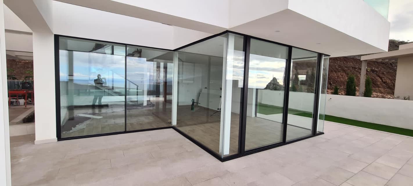 Una casa con muchas ventanas y puertas corredizas de vidrio.