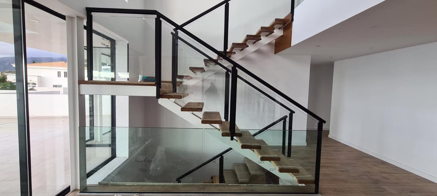 Una habitación vacía con una escalera y una barandilla de cristal.
