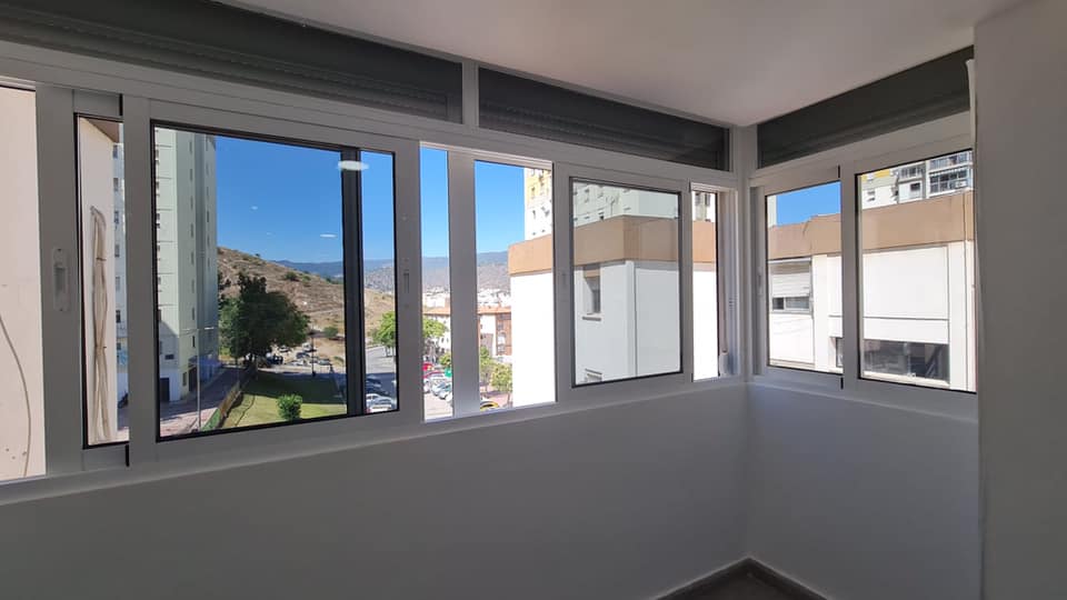 Una habitación con muchas ventanas y vista a un edificio.