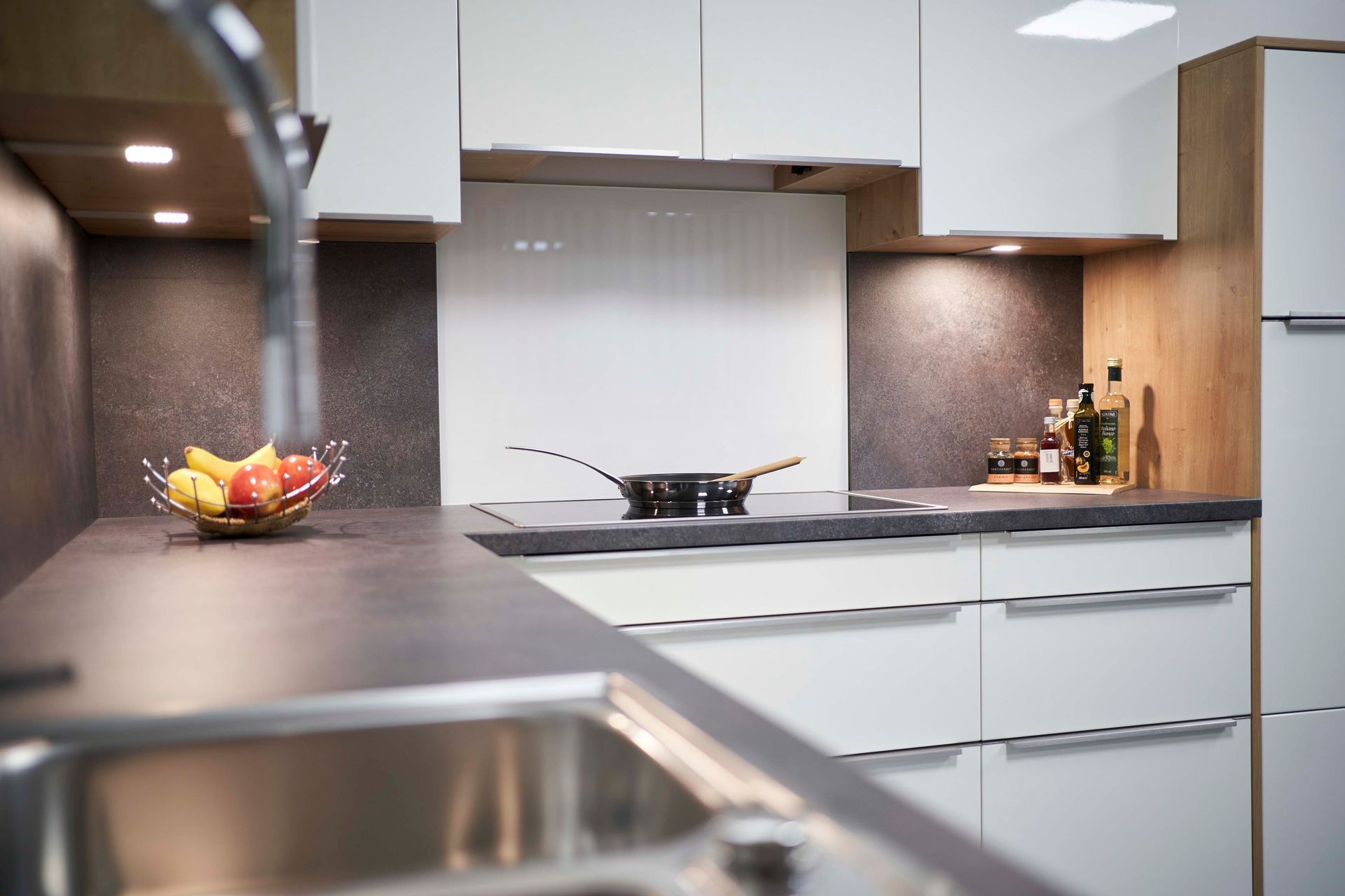 eine Küche mit weißen Schränken , einem Spülbecken und einer Pfanne auf dem Herd