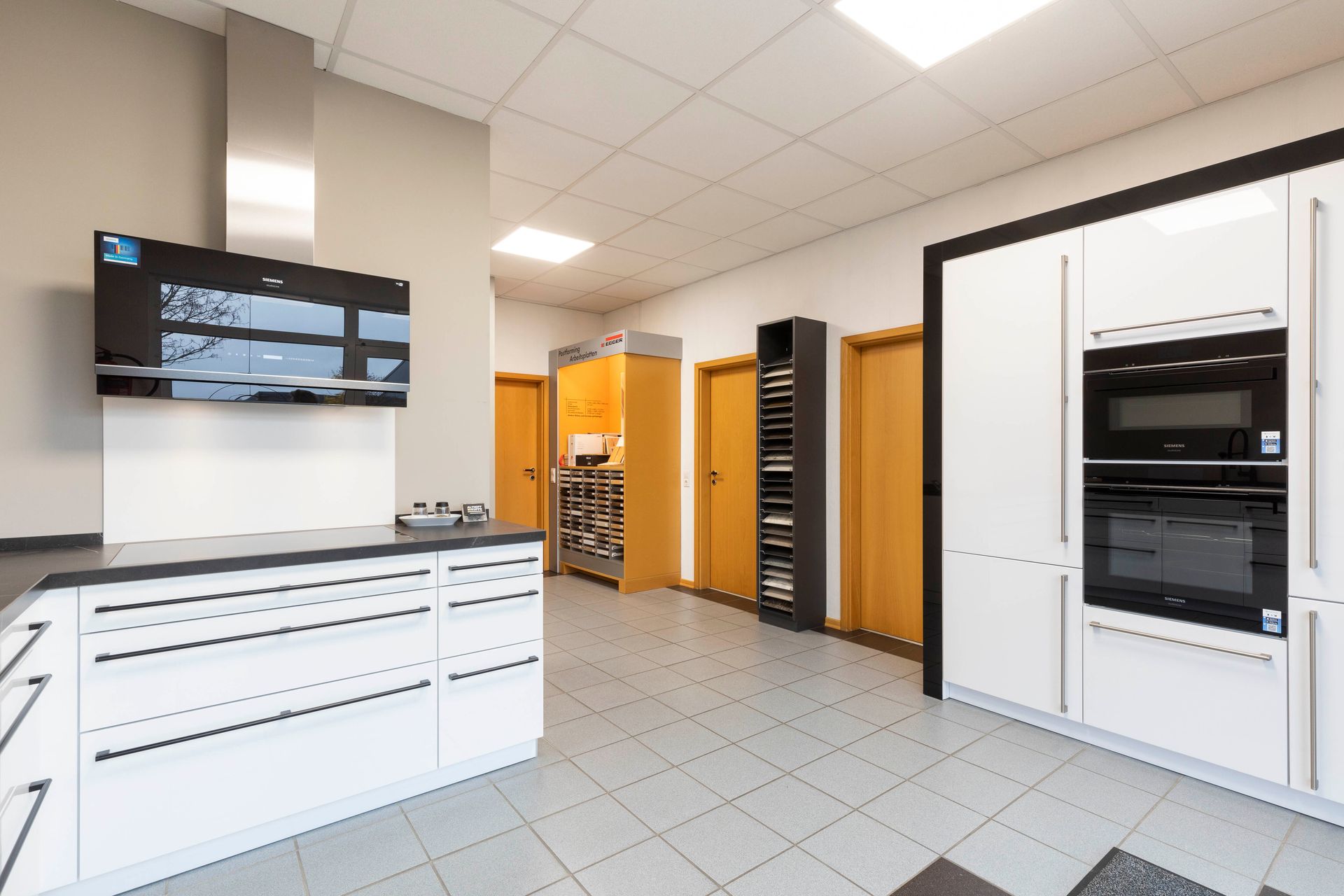 eine Küche mit weißen Schränken und schwarzen Geräten