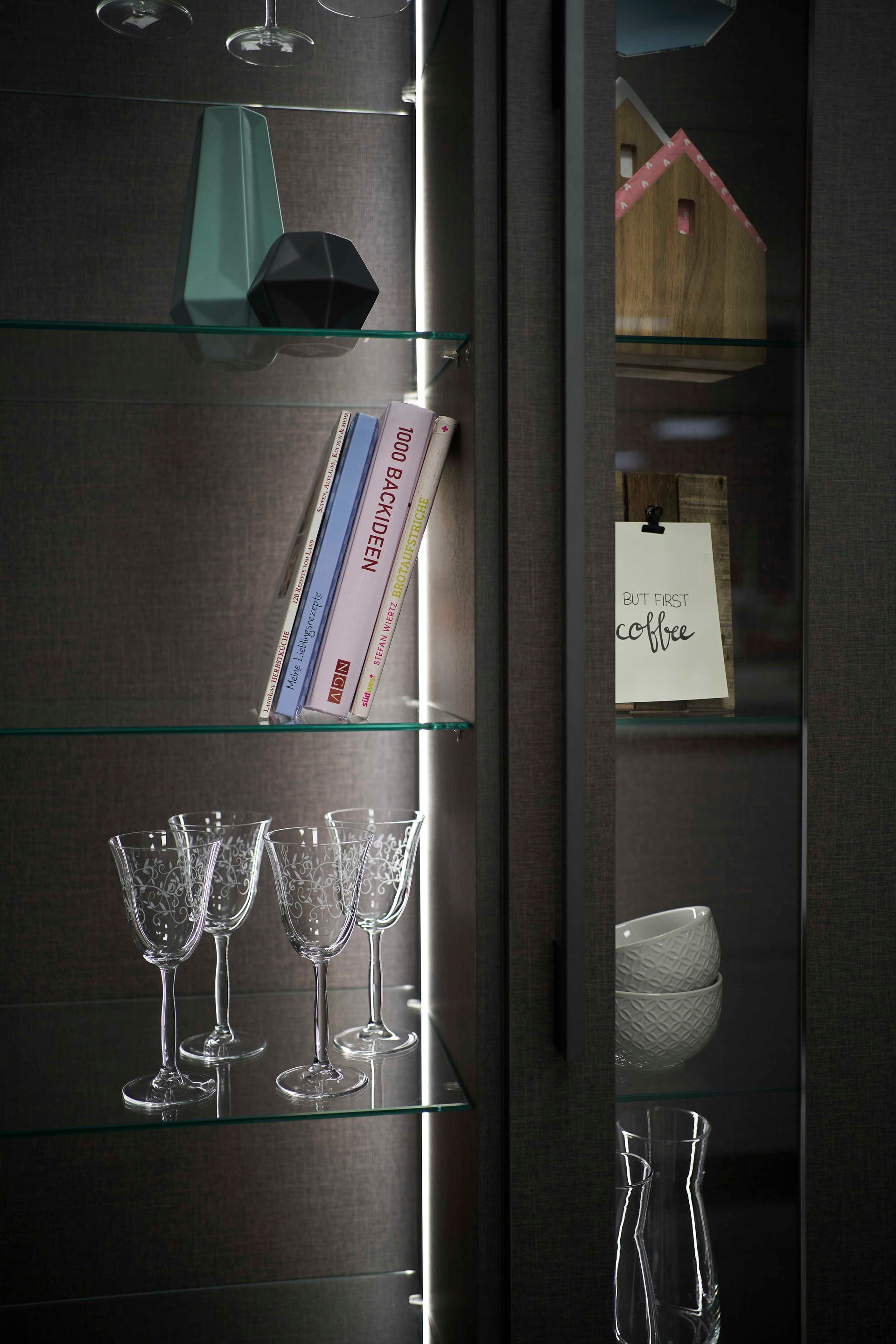 ein Schrank mit Gläsern und einem Buch darauf