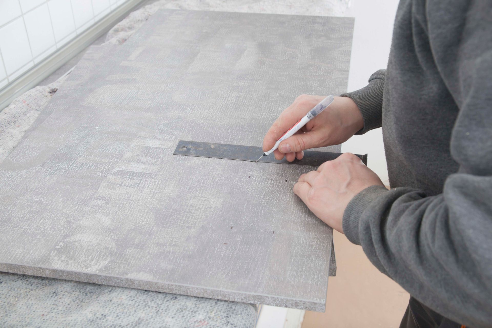 Ein Mann zeichnet mit einem Bleistift auf einen Betonblock