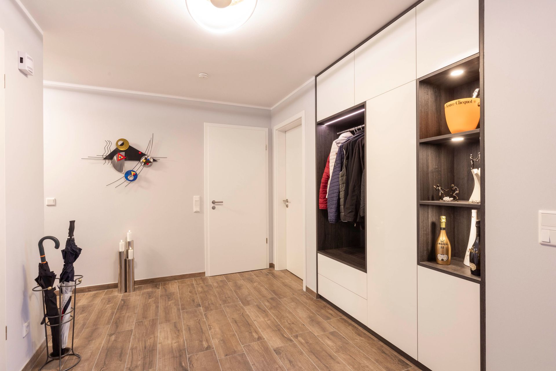 Ein Flur mit Holzboden , weißen Wänden und Regalen