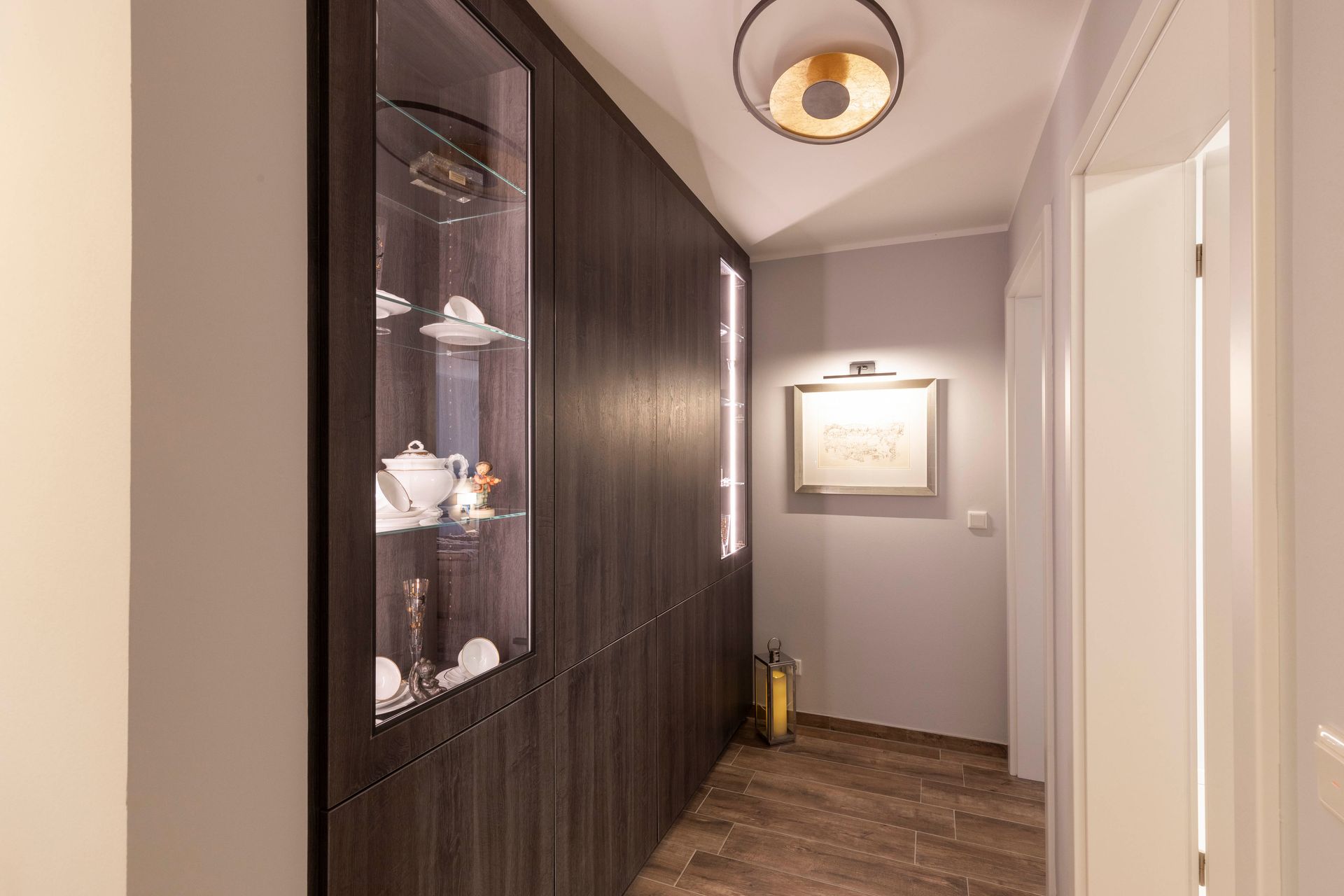 Ein Flur mit einer Glasvitrine und einem Bild an der Wand