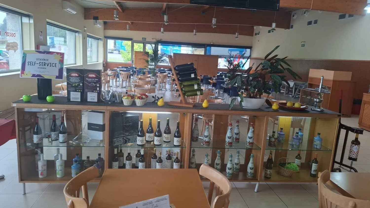 Mostrador de cafetería con vitrinas de cristal, botellas y estantes en un interior cálidamente iluminado