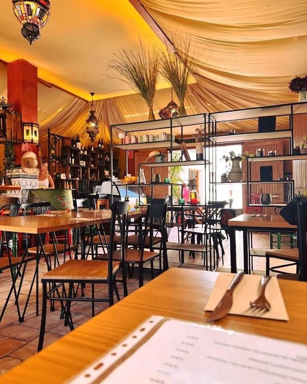 Interior acogedor de un restaurante con iluminación cálida, mesas, sillas y un menú en primer plano.