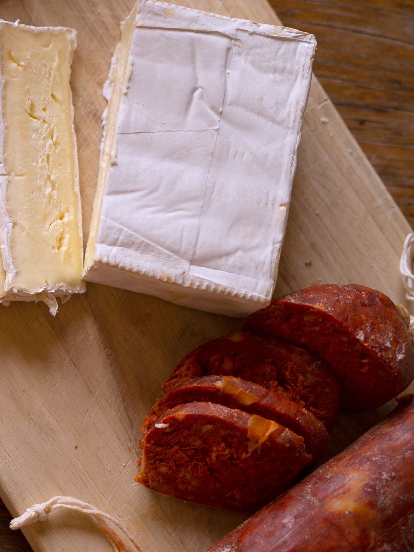 Surtido de quesos y salami en rodajas sobre una tabla de cortar de madera.