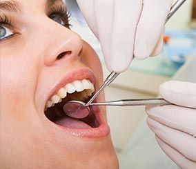 Boca de mujer abierta, herramientas dentales en uso. Inspección de dientes en una consulta dental.