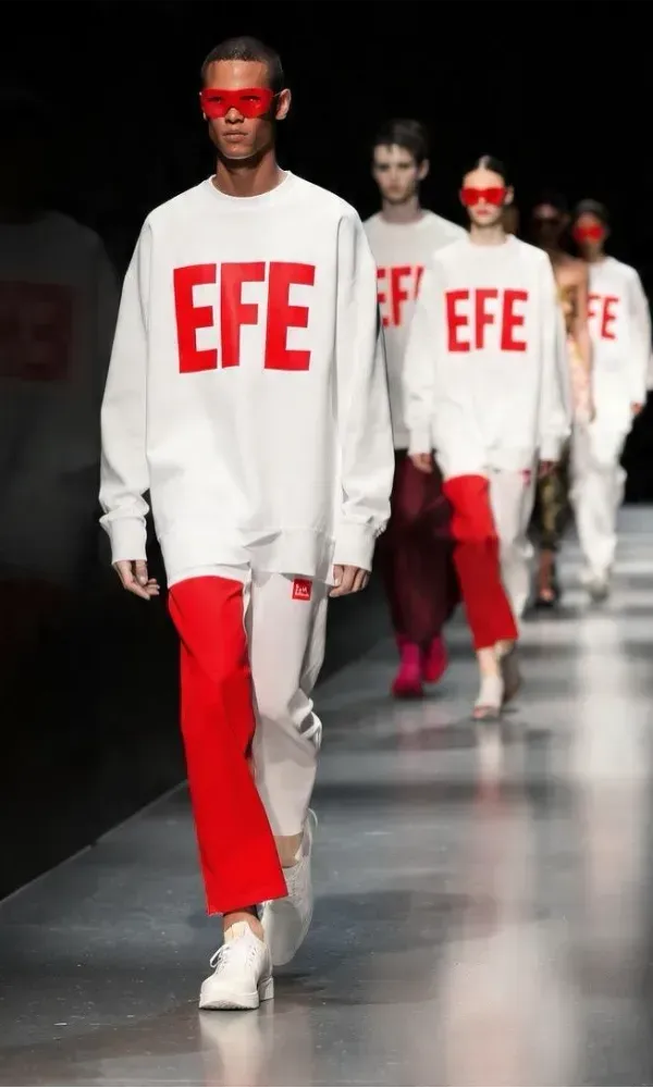 Modelo en la pasarela antes del desfile de EFE Fashion España, con el gran logotipo rojo de EFE en lo alto.