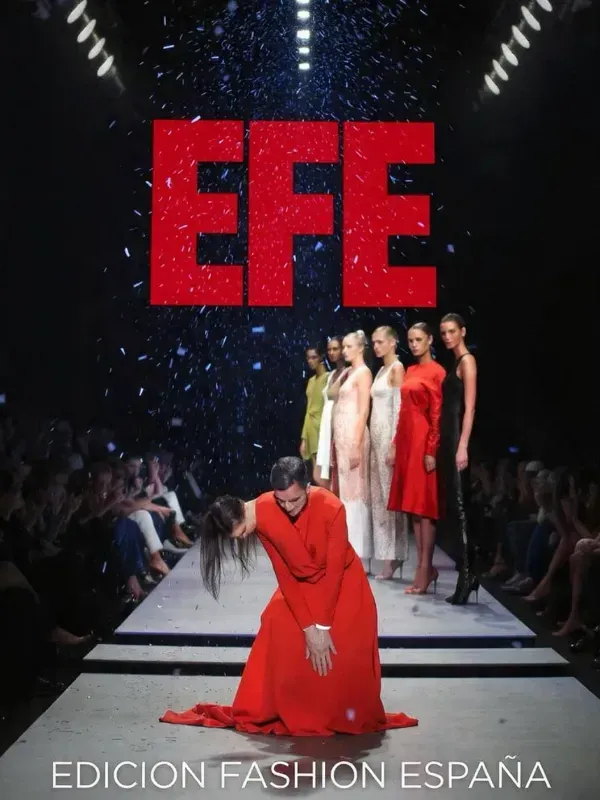 Modelo en la pasarela antes del desfile de EFE Fashion España, con el gran logotipo rojo de EFE en lo alto.