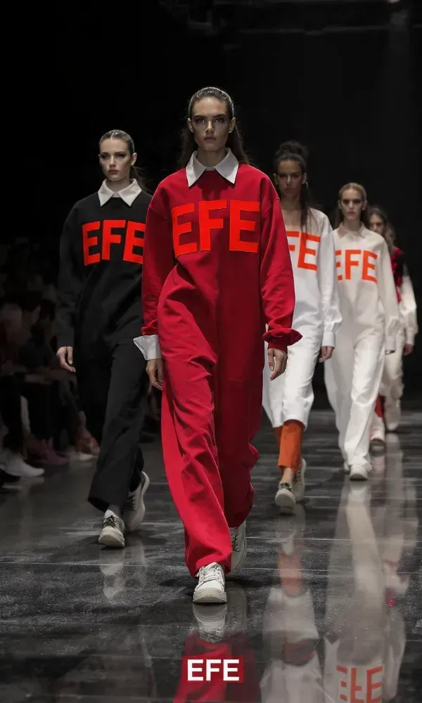 Desfile de moda con cinco modelos vestidas con vestidos negros y rojos bajo el título “Modelos en pasarela”.