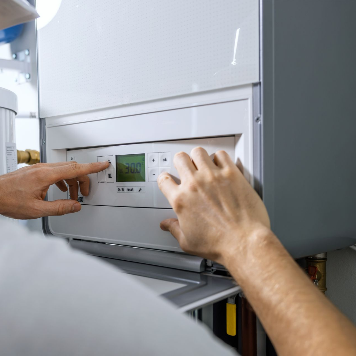 Une personne règle les commandes d'un appareil de chauffage blanc doté d'un petit écran.