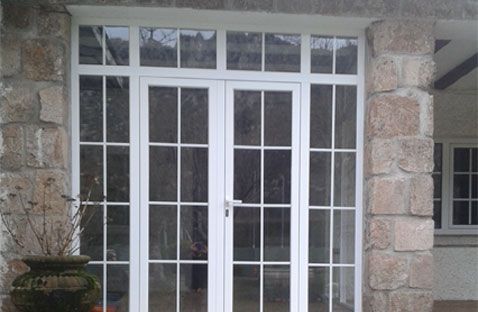 Puertas francesas blancas con paneles de vidrio en la fachada de piedra de un edificio