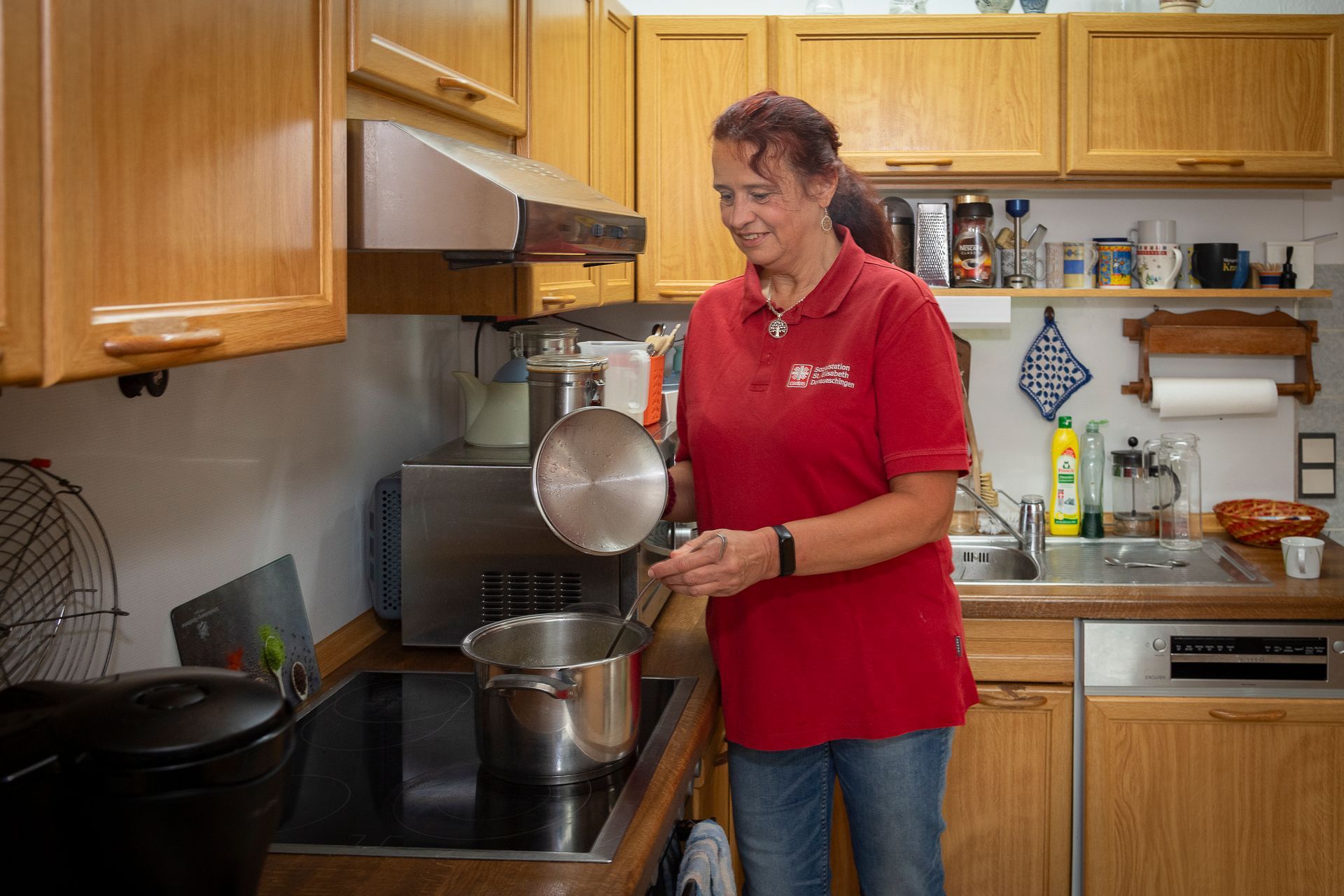 Eine Pflegerin mit einem Klemmbrett steht vor einem Dienstwagen