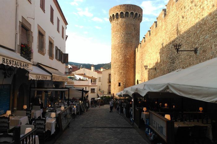 Un restaurante con mesas y sillas frente a una torre.