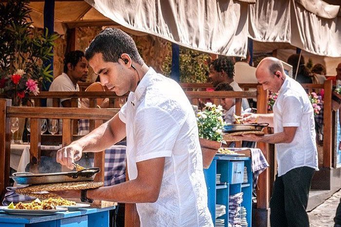 Dos hombres con camisas blancas están preparando comida en un restaurante.