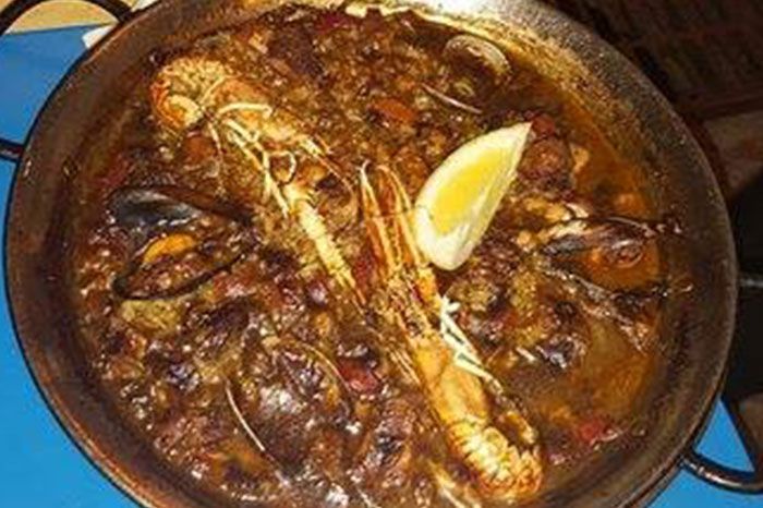 Una sartén con comida y una rodaja de limón encima.