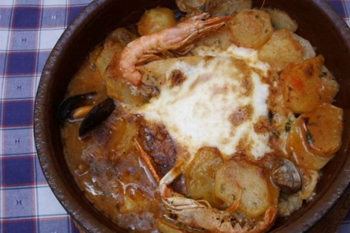 Un plato de comida con camarones y patatas sobre un mantel a cuadros.