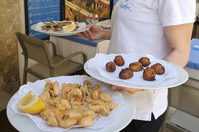 Una camarera sostiene dos platos de comida en sus manos.