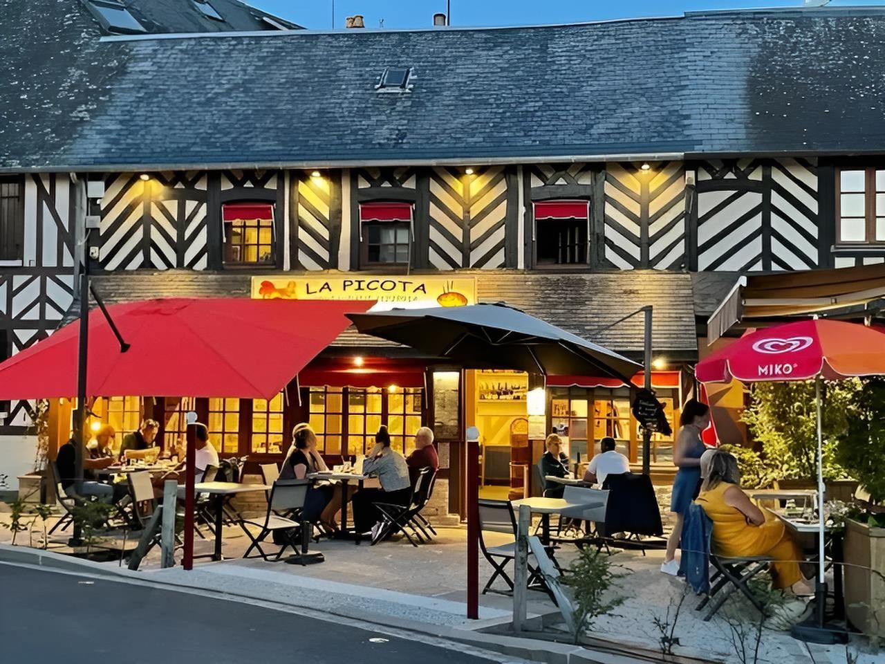 Restaurant « La Picota » avec terrasse ombragée par des parasols rouge et noir. Bâtiment à colombages.