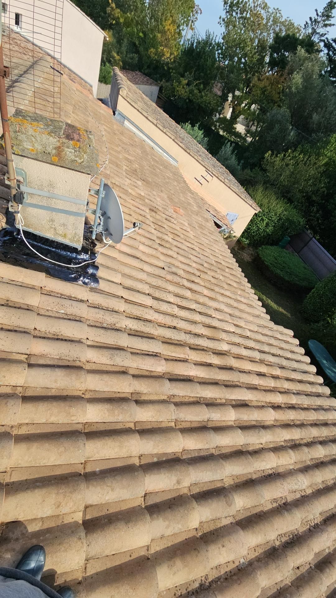 Toit en tuiles brunes avec antenne parabolique.