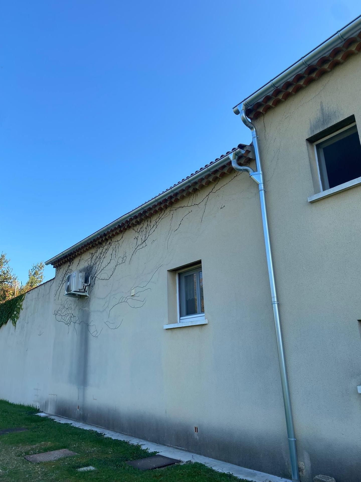 Bâtiment beige avec toit et gouttière.