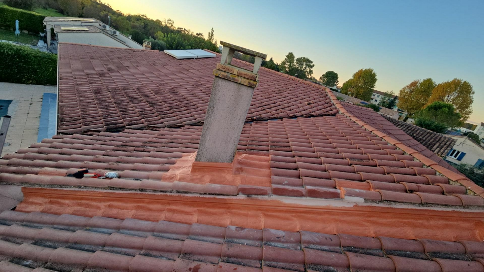 Toit de tuiles rouges avec cheminée et solins en cuivre.