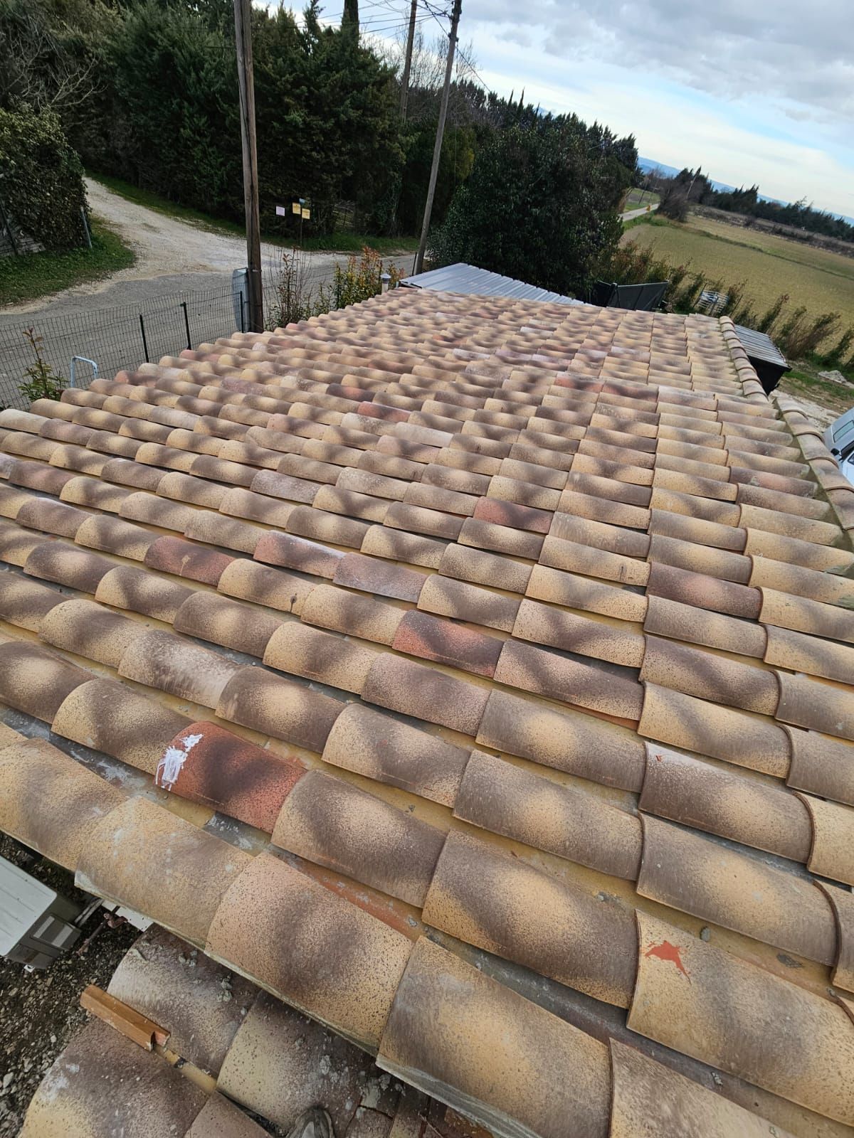 Vue en plongée d'un toit recouvert de tuiles canal en terre cuite.